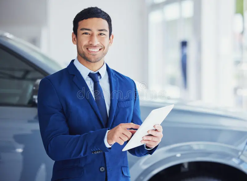 Service advisor reviewing a digital job card with customers beside a lifted vehicle